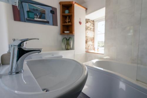 a bathroom with a sink and a bath tub at Idyllic Cornish cottage in the beautiful Lamorna valley - walk to pub & sea in Paul
