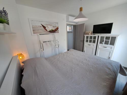 a white bedroom with a bed and a television at Vila Kamicić in Baška
