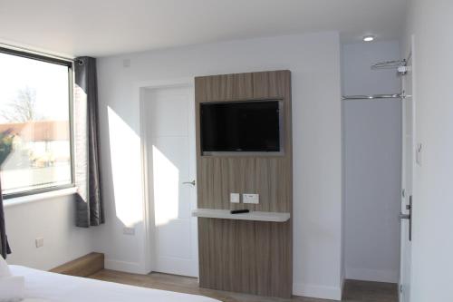 1 dormitorio con TV de pantalla plana en la pared en Sky Nights Hotel London Heathrow en Hillingdon