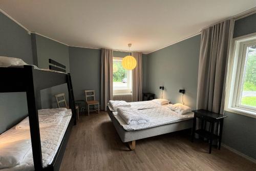 a bedroom with two beds and two windows at Vandrarhem Funäsdalen in Funäsdalen