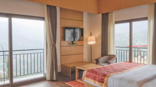 a bedroom with a bed and a tv and windows at Days Inn by Wyndham Gangtok Tadong in Gangtok