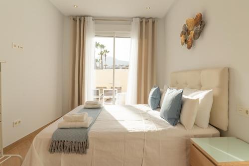 Un dormitorio con una gran cama blanca con ventana. en Atlantis Home PUERTO MARINA - 1 Minuto de la Playa, en Benalmadena Costa