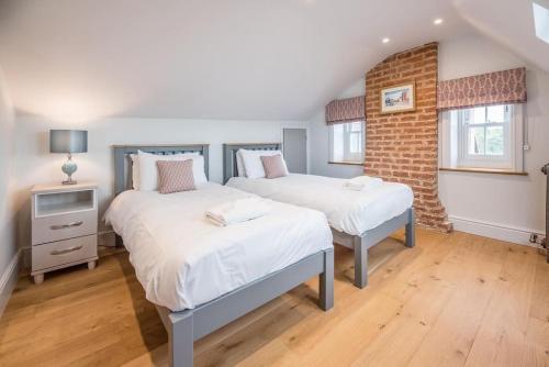 a bedroom with two beds and a brick wall at Quay View in Woodbridge