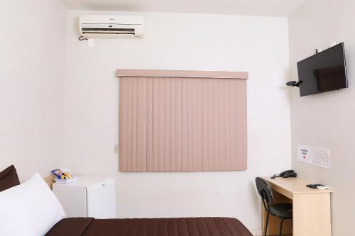 Habitación con cama y ventana con TV. en Hotel Borges en Quirinópolis