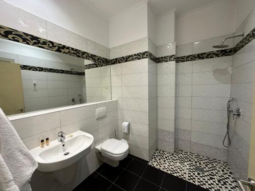 y baño con lavabo, aseo y espejo. en Edisem Hotel, en Tirana