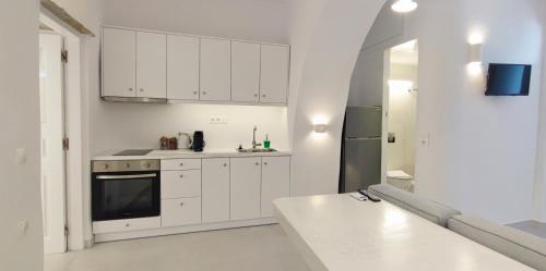 una cocina blanca con armarios blancos y fregadero en Cozy Now, en Tinos