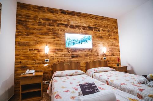 a bedroom with two beds and a wooden wall at Wellness Hotel Ristorante Baita Cerato in Bolca