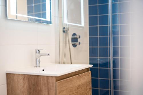 a bathroom with a sink and a shower with blue tiles at Huize Leeghwater in Zuidoostbeemster