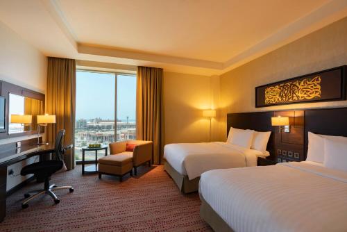 a hotel room with two beds and a desk at Courtyard by Marriott Jazan in Jazan