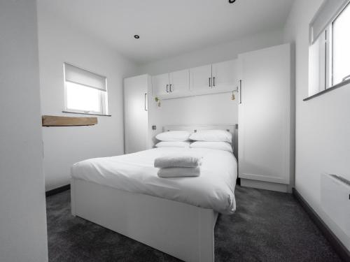 a white bedroom with a large white bed with two pillows at Goodstay Lodges by Urban Space in Barry
