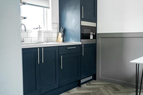 a kitchen with navy blue cabinets and a sink at Goodstay Lodges by Urban Space in Barry