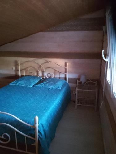sypialnia z łóżkiem z niebieską kołdrą i oknem w obiekcie Chambre w mieście Pontaubault