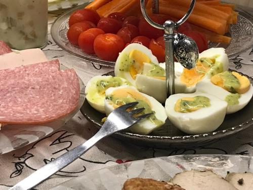 a plate of eggs and meat on a table with a fork at Landhaus Heidekrug in Hildesheim