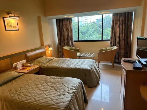 a hotel room with two beds and a television at Hotel Ashirwad in Pune
