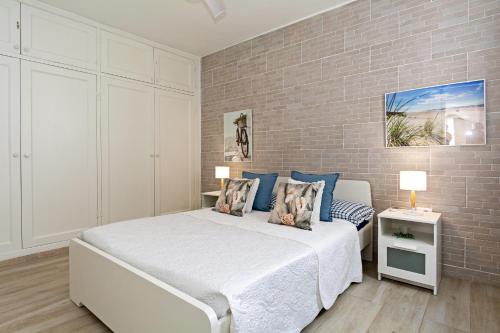 a bedroom with a white bed and a brick wall at 2BR Terrace Home - 10 min walk to the Beach in Playa Honda