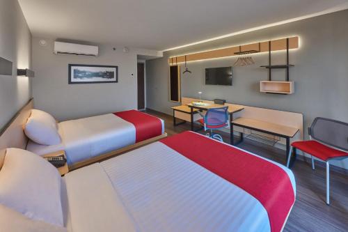 a hotel room with two beds and a table and chairs at City Express by Marriott Mérida in Mérida