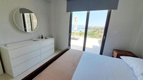 una camera da letto con un grande specchio e un letto bianco di Υπόσκαφα cave concept ad Ammouliani