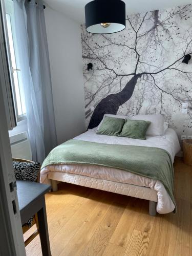 a bedroom with a bed with a tree mural on the wall at Zoralin in Concarneau