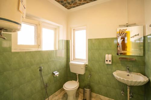a green bathroom with a toilet and a sink at goSTOPS Srinagar in Srinagar
