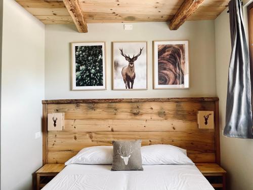 a bedroom with a bed and three pictures on the wall at La Maison - Il Riparo del Cervo in Bardonecchia