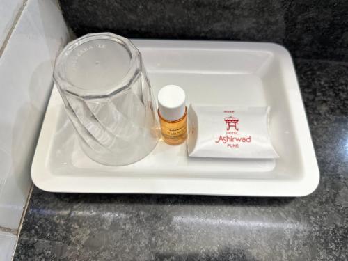 a white tray with a bottle of alcohol and a container at Hotel Ashirwad in Pune