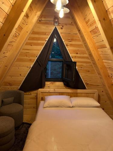 ein Schlafzimmer in einem Blockhaus mit einem Bett und einem Fenster in der Unterkunft Taşköprü Suit Bungalov in Hemşin