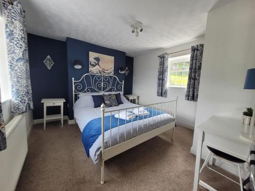 een slaapkamer met een bed met een blauwe muur bij Caudle Cottage, Ruardean in Lydbrook