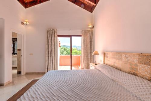 Luxury penthouse in Jardines de Don Carlos في مربلة: غرفة نوم بسرير كبير ونافذة كبيرة
