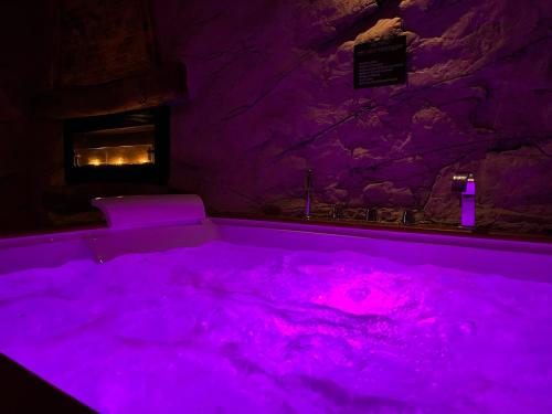 una vasca da bagno viola con luci rosa in una grotta di Wellness Hotel Ristorante Baita Cerato 