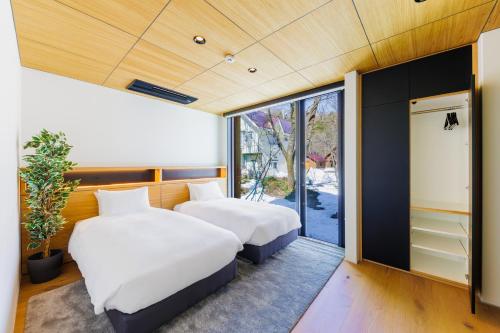 白馬村にあるCredence Chalets by HHGの大きな窓のある部屋にベッドが2つある