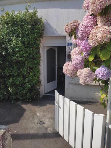 a white fence in front of a house with flowers at Ty Cado in Belz