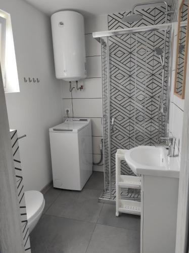 biała łazienka z toaletą i umywalką w obiekcie Domki na Polnej w Grzybowie