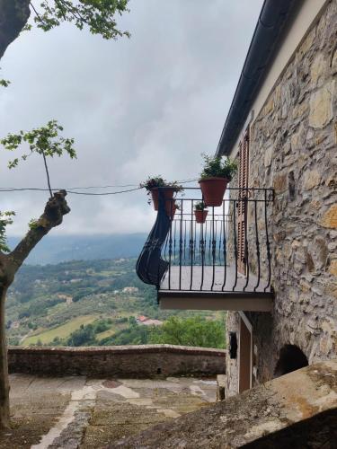 a balcony with potted plants on a stone building at La Casa di Antonietta in Fosdinovo