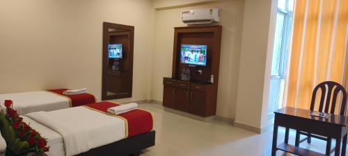 a hotel room with two beds and a flat screen tv at HOTEL PIONEER PARADISE in Nāgercoil