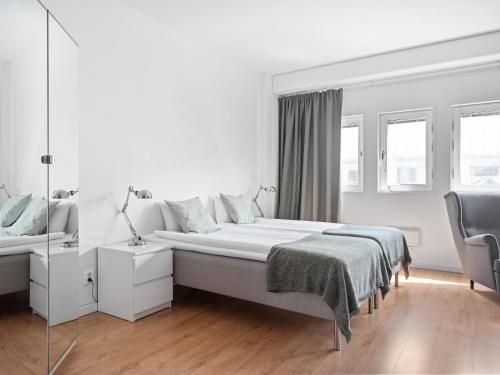 una camera bianca con un letto e una sedia di Part-Time Home Rotebro Station a Stoccolma