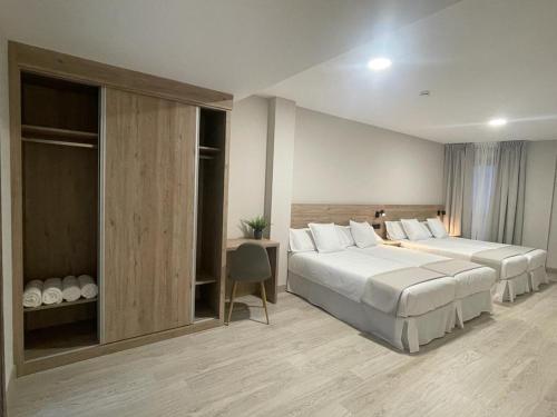 ein Hotelzimmer mit 2 Betten und einem Schreibtisch in der Unterkunft URBAN Pensión in Melide