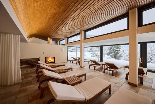 a living room with a fireplace and tables and windows at Wellness Hotel Stoos in Stoos