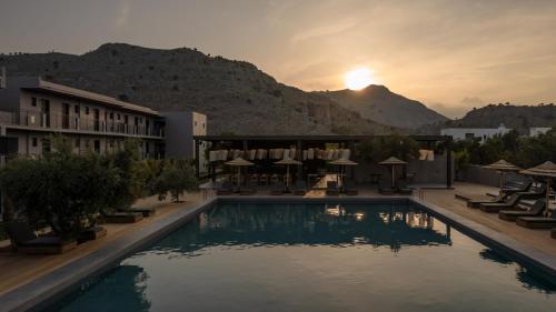 een hotel met een zwembad met een zonsondergang op de achtergrond bij Cook's Club Kolymbia Rhodes -Adults only in Kolimbia