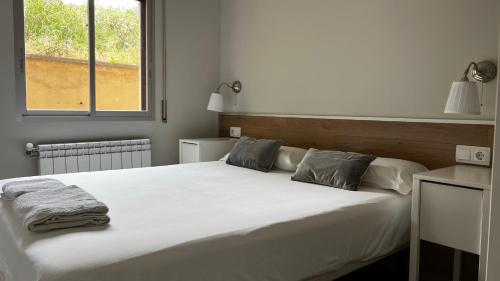 a bedroom with a large white bed with two pillows at Apartaments La Pertusa 1 in Corçà