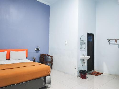 a bedroom with an orange bed and a sink at Reddoorz @ Hotel Bersaudara Bungo in Muarabungo