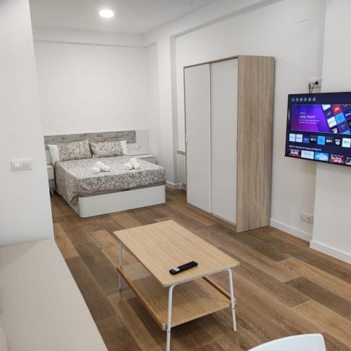 sala de estar con cama, mesa y TV en Garcia Noblejas Apartments, en Madrid