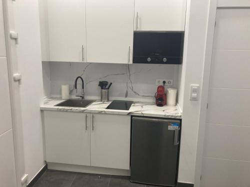 een keuken met witte kasten en een zwarte koelkast bij Ensanche1 Apartments in Madrid