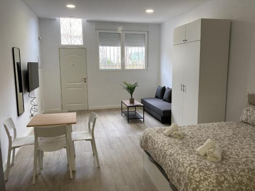 1 dormitorio con cama, mesa y sofá en San Sebastián Apartments, en San Sebastián de los Reyes