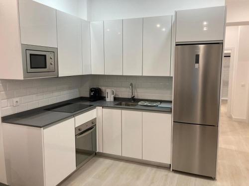 a kitchen with white cabinets and a stainless steel refrigerator at Matadero Apartments 3 in Madrid