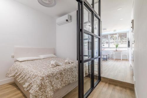 biała sypialnia z łóżkiem i szklaną ścianą w obiekcie Arturo Soria Apartments2 w Madrycie