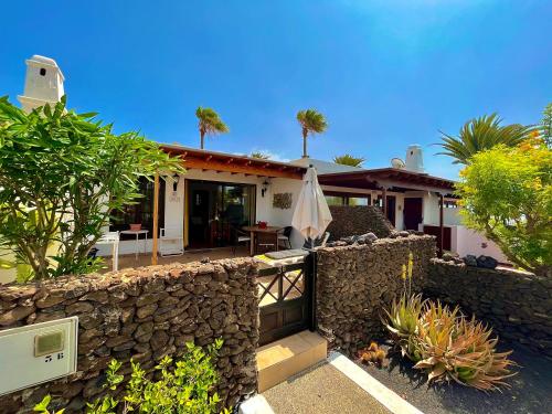 een huis met een stenen muur en een paraplu bij Casas del Sol in Playa Blanca