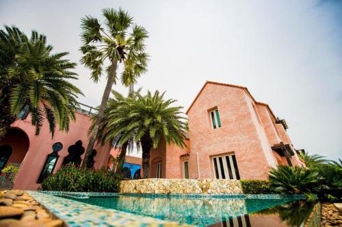 a building with palm trees and a swimming pool at Villa Maroc Resort in Pran Buri