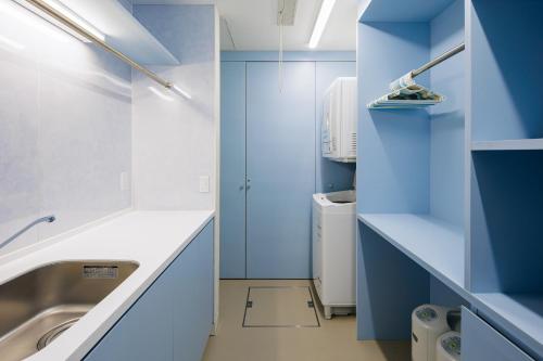 baño con paredes azules y lavamanos en AMO 54 by Hakuba Hotel Group, en Hakuba