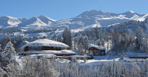 un bâtiment recouvert de neige avec des montagnes en arrière-plan dans l'établissement Wellness Hotel Stoos, à Stoos