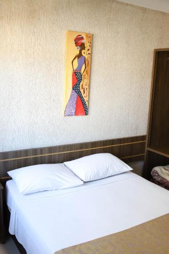 a bedroom with a bed with a painting on the wall at Hotel Holiday Foz in Foz do Iguaçu